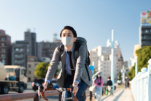 Asian young man in business casual clothing commuting with bicycle in Tokyo, Japan