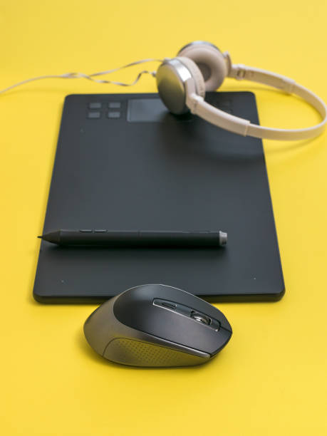 istock Graphic tablet, headphones and mouse on a yellow background. 1285715636