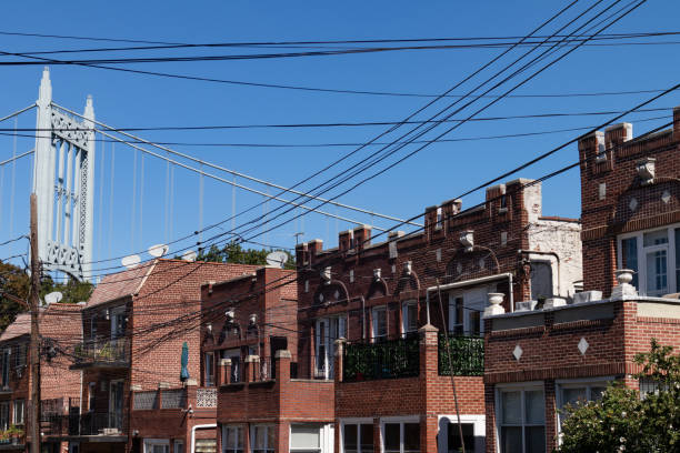 Row of Old Brick Homes with the Triborough Bridge in Astoria Queens New York A row of similar brick homes and telephone wires with the Triborough Bridge in the background in Astoria Queens of New York City queens new york city stock pictures, royalty-free photos & images