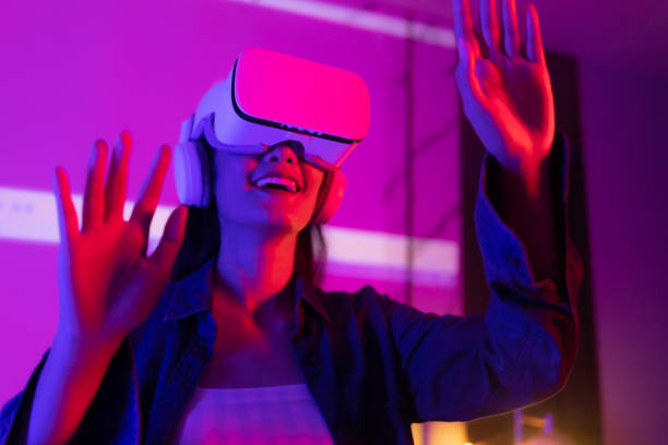 istock Young asian woman is using virtual reality headset. Neon light studio portrait. Concept of virtual reality, simulation, gaming and future technology.Asian woman play game in bedroom. 1285719733
