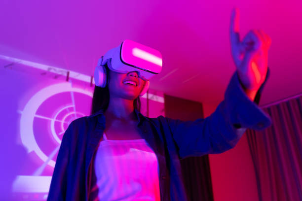 istock Young asian woman is using virtual reality headset. Neon light studio portrait. Concept of virtual reality, simulation, gaming and future technology.Asian woman play game in bedroom. 1285720244
