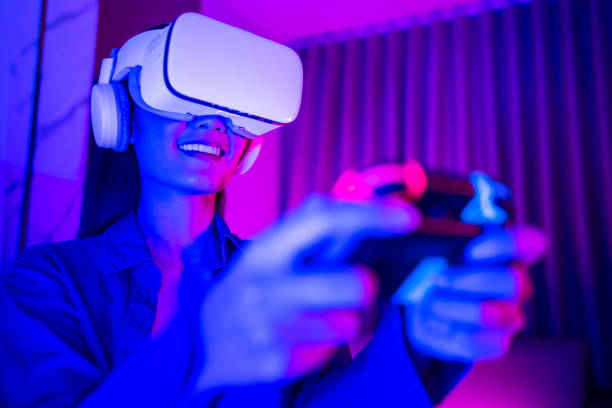 istock Young asian woman is using virtual reality headset. Neon light studio portrait. Concept of virtual reality, simulation, gaming and future technology.Asian woman play game in bedroom. 1285720253