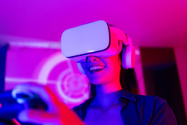 istock Young asian woman is using virtual reality headset. Neon light studio portrait. Concept of virtual reality, simulation, gaming and future technology.Asian woman play game in bedroom. 1285720264