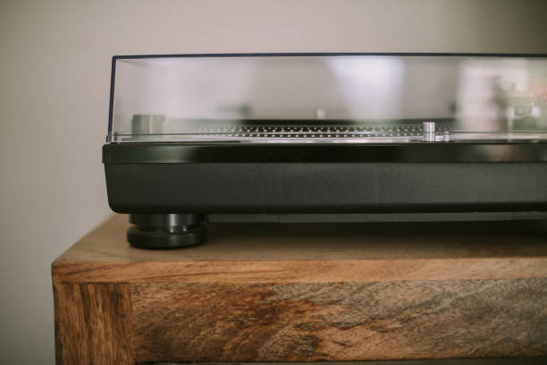 Sleek, modern, black and clear plastic record player sitting on a stained wooden surface.