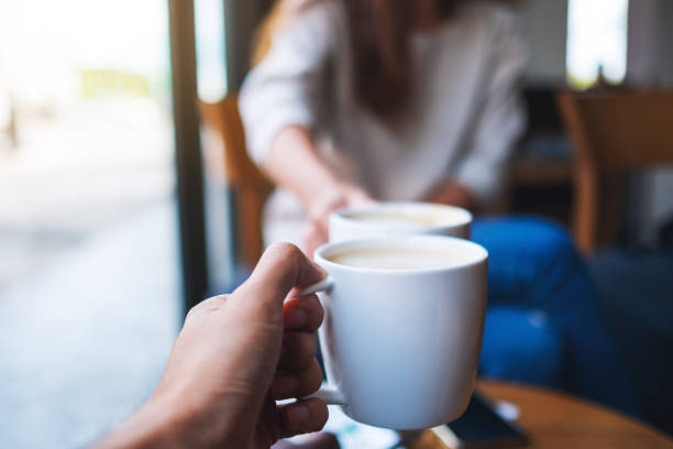 istock man and woman clinking white coffee mugs in cafe 1285724335