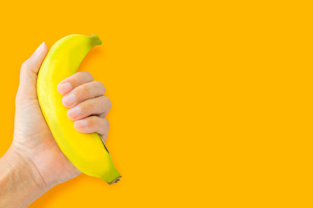 istock Hand holding a yellow banana on a yellow background with copy space 1285726661