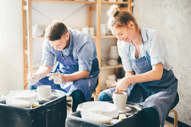 Couple in love working together on potter wheel in craft studio workshop. stock photo