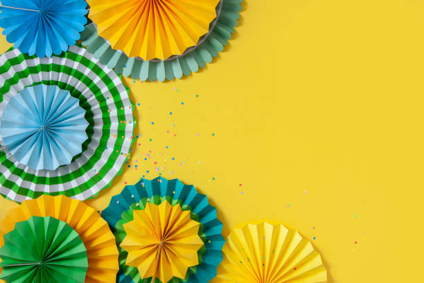 istock Multicolored paper rosettes of various sizes on a yellow background. Decoration and decor for party, birthday or holiday 1285731469