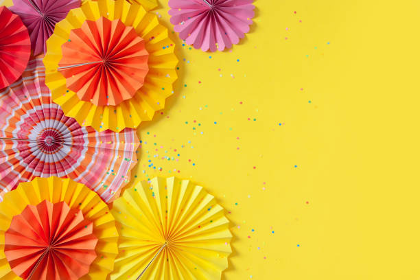 istock Multicolored paper rosettes of various sizes on a yellow background. Decoration and decor for party, birthday or holiday 1285731487
