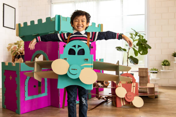 istock Cute kids playing while parents relaxing at home together, smiling active boy entertaining with paper toy,rocking horse , happy family spending time together in living room on weekend.Asian family happy time concept. 1285741082