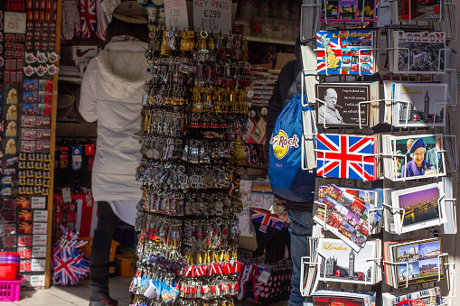 Gift Shop in City of Westminster, London, showing people inside shopping and postcards of the Queen and of Winston Churchill.