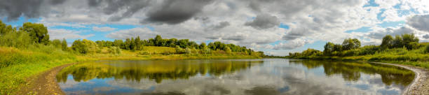 istock Summer panoramic landscape with calm river and beautiful clouds in blue sky 1285742966