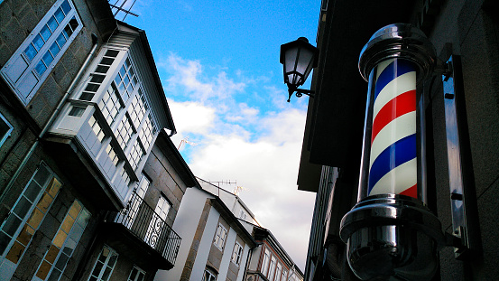 Barbershop old fashioned symbol in old town street. Red and blue moving cylinder. Galería, old-fashioned street light. Lugo city, Galicia, Spain.