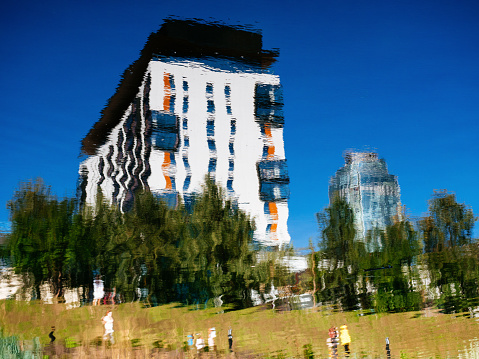 Yekaterinburg, Russia, August 27, 2020: the Kandinsky residential building is reflected in the river. Luxury real estate in the city center. Beautiful city embankment