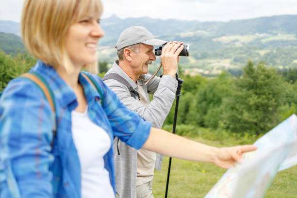 istock Young woman holding a map standing by her father using binoculars during hike 1285752300