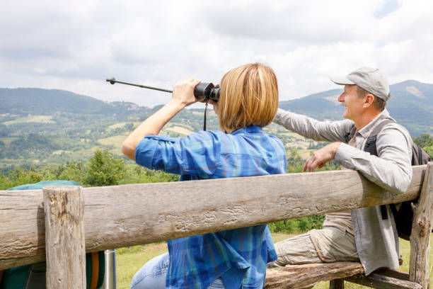 istock Senior man pointing with trekking pole and woman looking through binoculars 1285752320