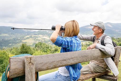 Young woman using binoculars and senior man pointing direction via trail trekking pole