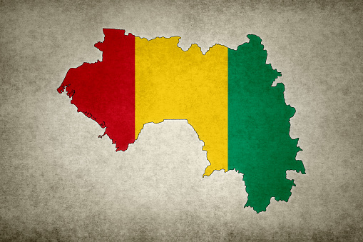 Grunge map of Guinea with its flag printed within its border on an old paper.