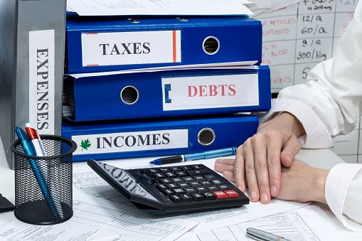 Still person’s hands on a desk , accounting documents of  incomes, expenses and taxes of a company, concept of work in accountant department, closeup view