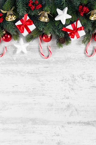 Christmas background with fir tree,  gift boxes, and Christmas ornaments with candy canes on white wooden background