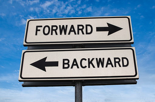 Forward vs backward. White two street signs with arrow on metal pole with word. Directional road. Crossroads Road Sign, Two Arrow. Blue sky background. Two way road sign with text.