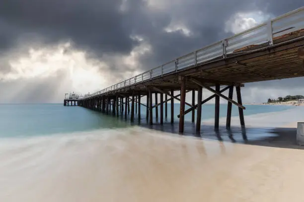 Malibu Pier beach with motion blur and storm sky near Los Angeles in Southern California.