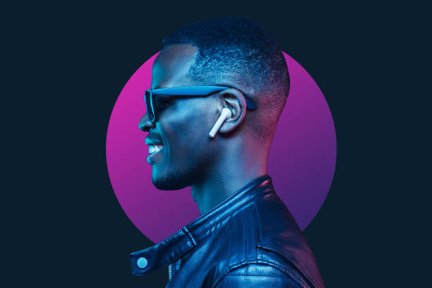 retrato de neón de un hombre americano africano sonriente escuchando música con auriculares, usando chaqueta de cuero negro - radio hardware audio fotos fotografías e imágenes de stock