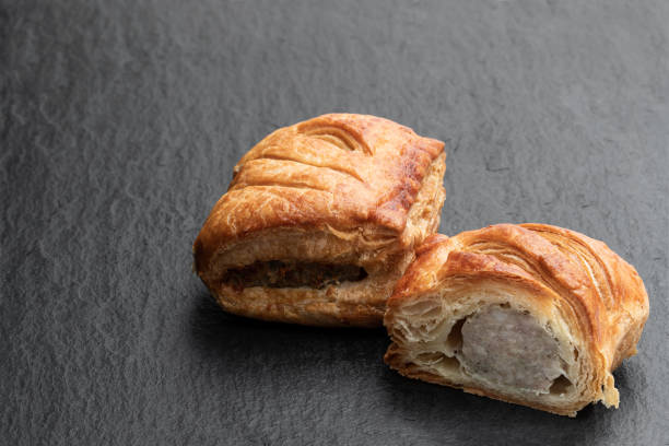 istock Sausage meat in puff pastry on black stone background 1285767961