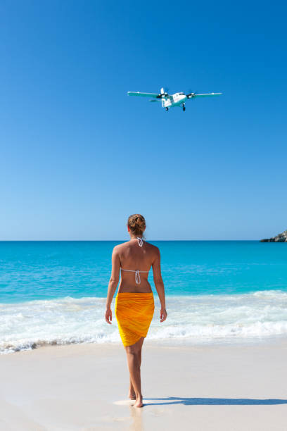 istock woman standing on a tropical beach with plane flying over 1285767972