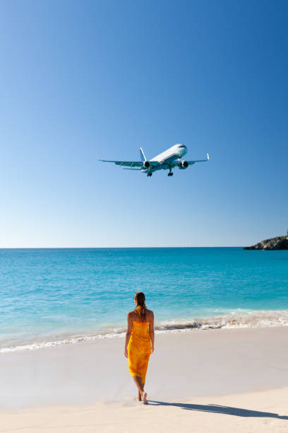 istock woman standing on a tropical beach with plane flying over 1285767974
