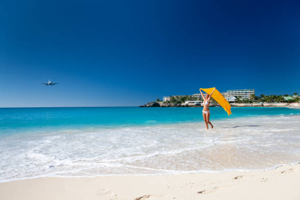 istock happy woman on a tropical beach with plane flying over 1285767978