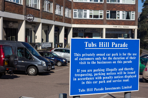 Tubs Hill Parade in Sevenoaks, England. Shops and cars are in the background and a parking notice is from Tubs Hill Parade Investments.