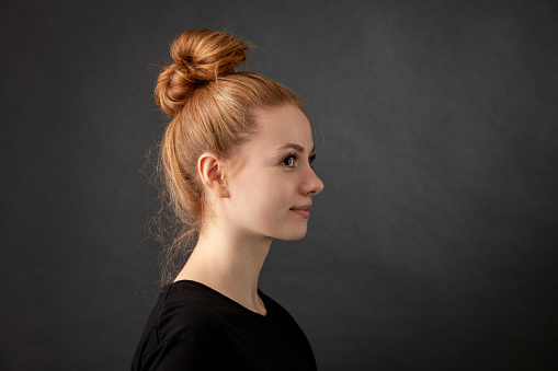 Close up studio portrait of 22 year old red-haired woman in black t-shirt on black background