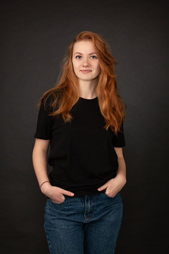 Close up studio portrait of 22 year old red-haired woman in black t-shirt on black background