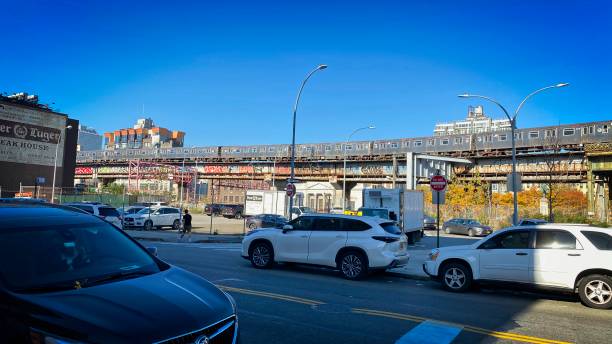 Subway train on Williamsburg Bridge Brooklyn, NY, USA - Nov 15, 2020: A subway train at the foot of the Williamsburg Bridge above a parking lot on a bright sunny day warren street brooklyn stock pictures, royalty-free photos & images