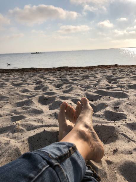 istock Bare feet and jeans on the beach overlooking the calm sea 1285774496