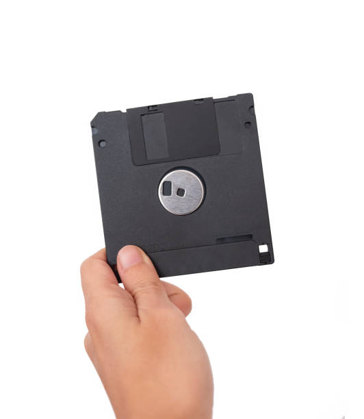 istock Female Hand Holding A Black Floppy Disk (Back Side) 1285778060