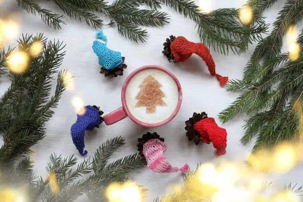 cones in multi-colored caps around a cup with frothy cappuccino and a Christmas tree pattern top view