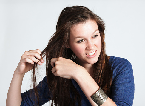 Young woman adjusts her long brown hair.