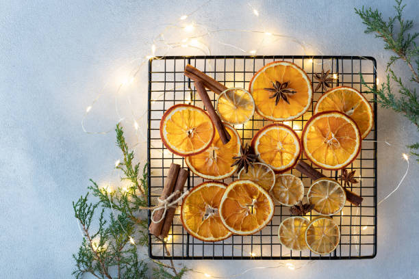 naranjas secas, limones, palitos de canela y estrellas de anís sobre un fondo de luces de navidad y ramas de abeto - fruit winter orange lemon fotografías e imágenes de stock