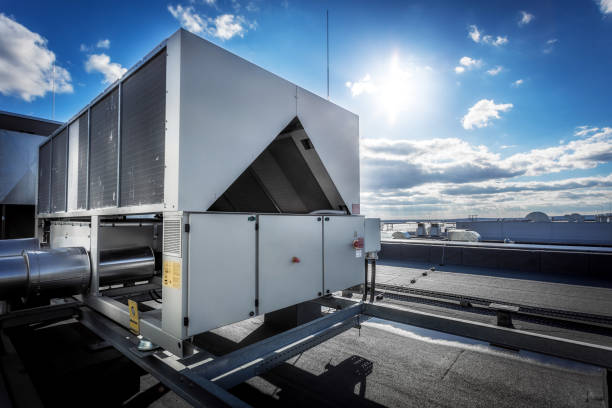 Huge air conditioning unit on the roof of building A huge air conditioning unit on the roof of the building. In the background of blue sky with shining sun. Focus is at the front of the air conditioner, the other parts of image slightly blurred. duct stock pictures, royalty-free photos & images