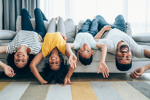Shot of a cheerful family hanging upside down on the sofa at home.
