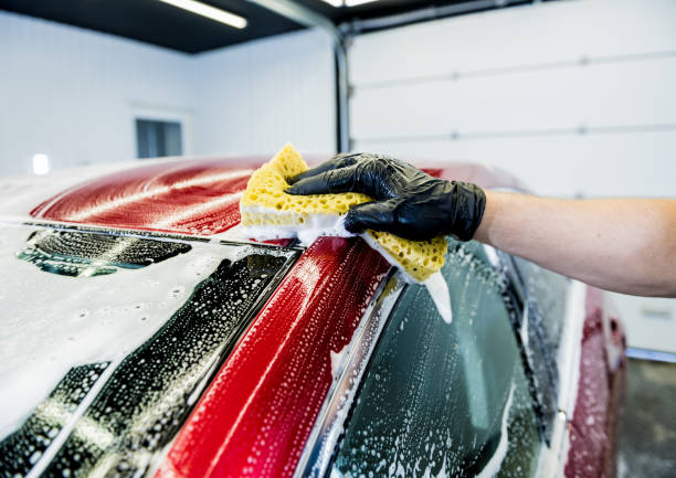 istock Worker washing red car with sponge on a car wash 1285787685