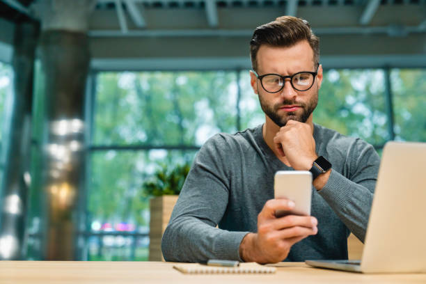 istock Serious young businessman checking his phone during working process with laptop on office desk 1285788514