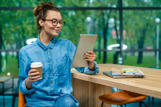 istock Smiling cheerful young businesswoman using her tablet during coffee break in office 1285788544