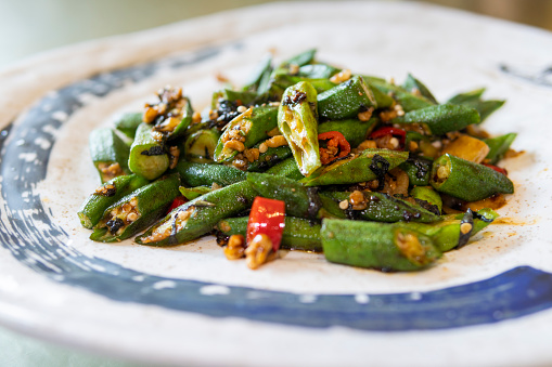 Stir-fried French Beans with Minced Pork and Preserved Olive Vegetables with chopsticks served in a dish isolated on mat side view on grey background