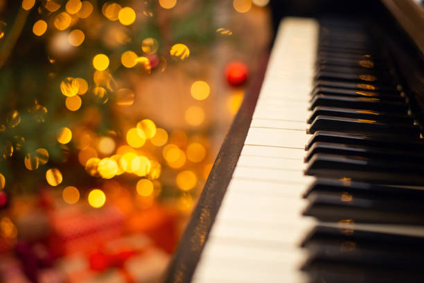 Piano keyboard with bright christmas lights on the background. stock photo