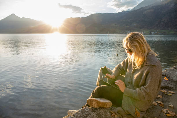 istock Woman relaxes by lakeside at sunise 1285789291