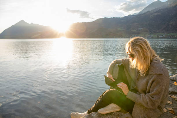 istock Woman relaxes by lakeside at sunise 1285789395