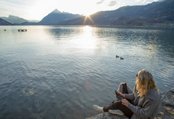 istock Woman relaxes by lakeside at sunise 1285789900